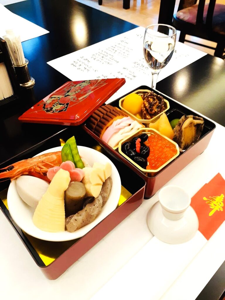 インディペンデンスヴィレッジ成城西のお正月|祝い膳の重箱料理と盃(黒豆・数の子・いくら・栗きんとん・紅白かまぼこ・煮しめ)